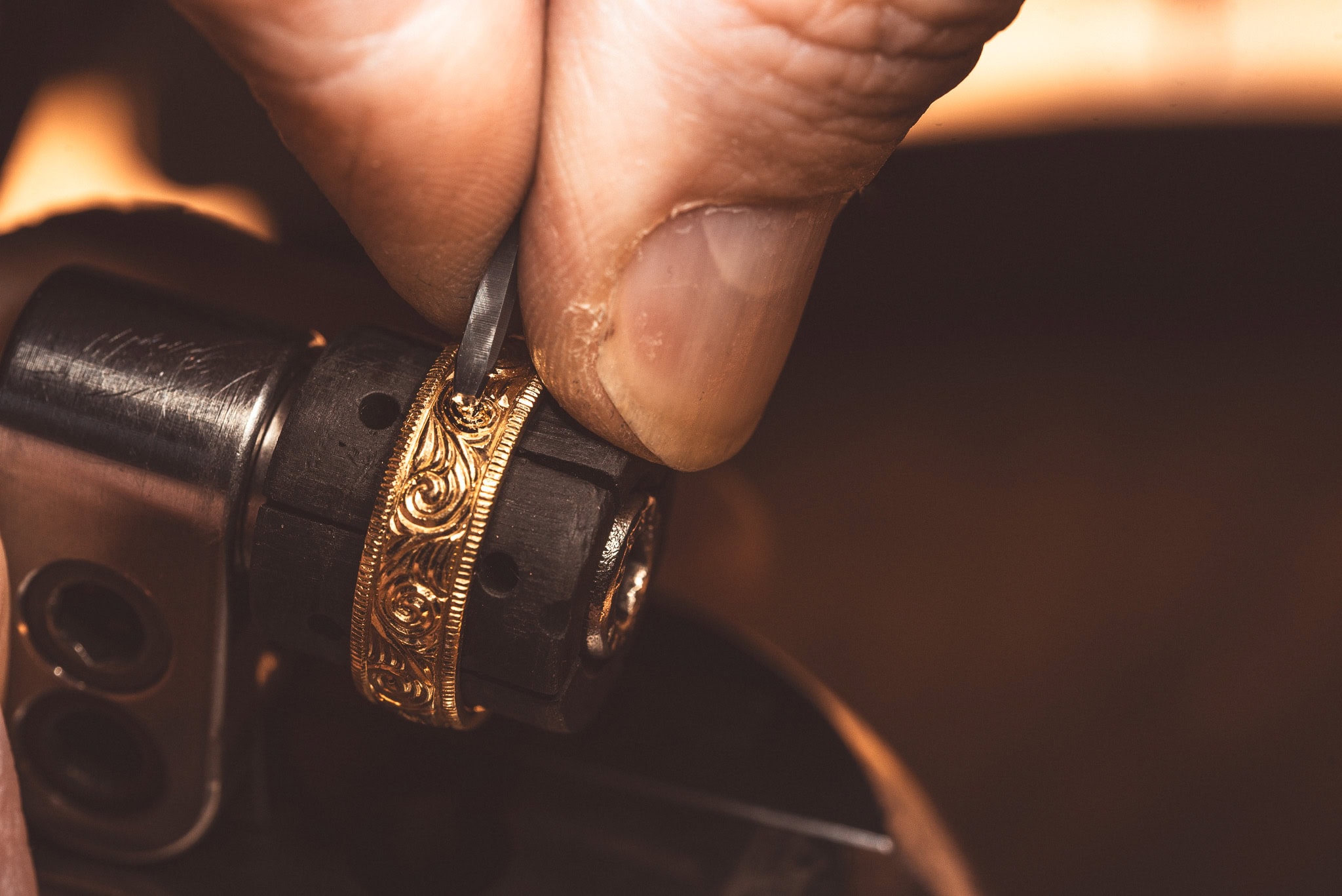 Auf dem Bild sieht man eine Hand, die einen Goldring graviert