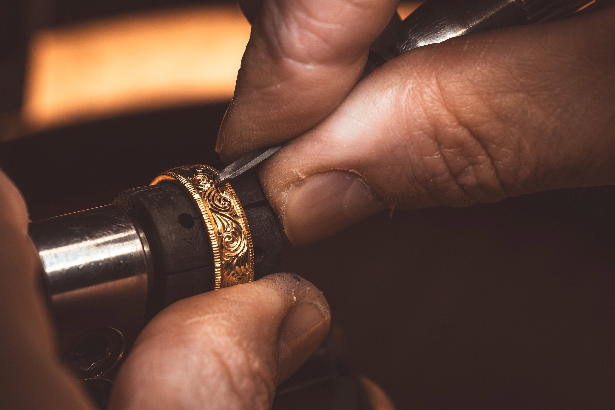 Auf dem Bild sieht man eine Hand, die eine Goldring graviert
